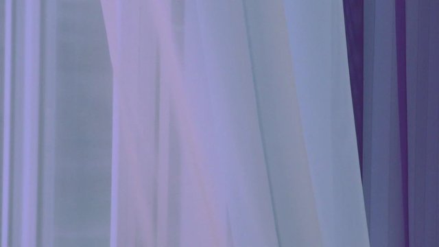 A gust of wind from the room through the window. A soft purple curtain in the breeze.