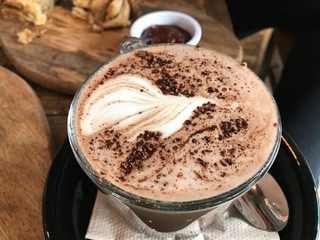 Coffee with beautiful foam and sprinkled with cinnamon or cocoa, vegan version of tasty coffee with oat milk in cafe house
