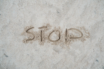 Stop sign drawn on beach sand.