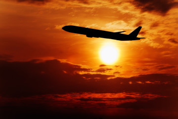 Naklejka na ściany i meble Airplane fly on sunset sky. Airplane in the sky at sunrise