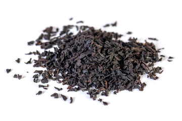 A pile of dried black tea leaves on a white background.