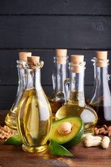 Useful vegetable oils in glass bottles. Avocado oil, chickpea oil, linseed oil, peanut oil, almond oil. Dark wooden background