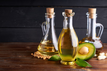 Healthy vegetable oils in glass bottles. Avocado oil, chickpea oil, peanut oil, almond oil. Dark background