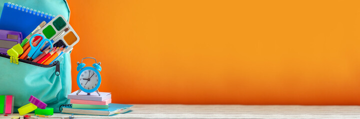 Concept back to school. Full turquoise School Backpack with stationery on table. Banner.