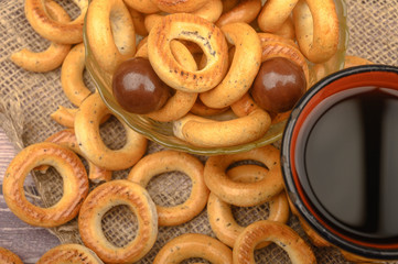 Small bagels, chocolates, a mug of tea and a rough homespun cloth on a wooden background close-up.