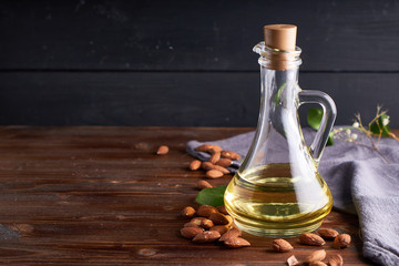 Obraz na płótnie Canvas Useful Almond oil in glass bottles. Dark wooden background Copyspace