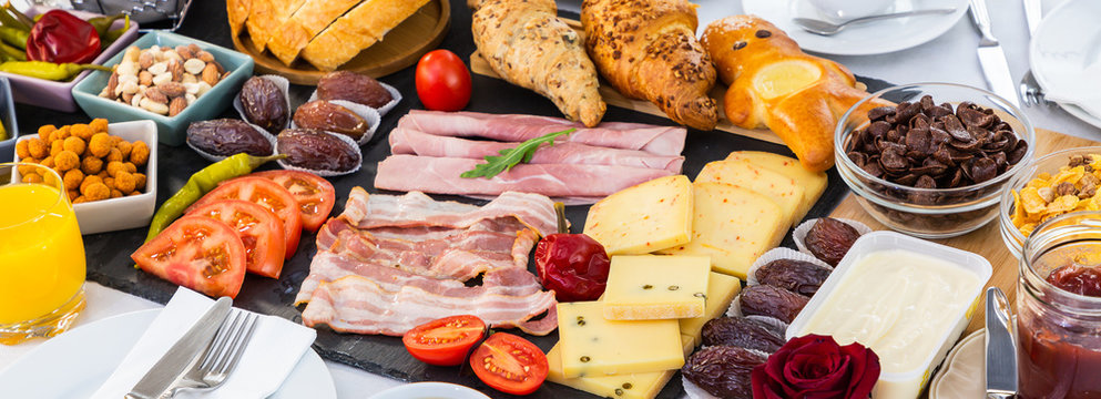 Breakfast on the table. Croissant bread, Croissant cereal, Bacon, ham, cheese, lettuce, beans, corn flakes, fruit, coffee, tea, and orange juice is breakfast. , Lunch or dinner for every day