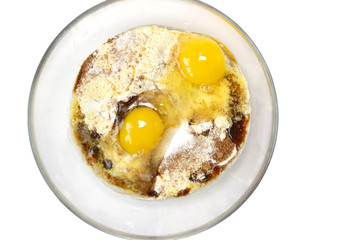 Corn and rice flour, coconut sugar, two eggs in the transparent plate. Making a cake. Mixing the dough. White background. Copy space. Place for text and design. Top view. Flat lay. 