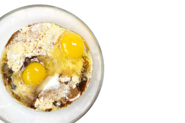 Corn and rice flour, coconut sugar, two eggs in the transparent plate. Making a cake. Mixing the dough. White background. Copy space. Place for text and design. Top view. Flat lay. 