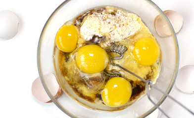 CoCorn and rice flour, coconut sugar, four eggs in the transparent plate. Making a cake. Mixing the dough. White background. Copy space. Place for text and design. Top view. Flat lay. Gluten-free reci