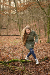 young, happy, long-haired teenager runs through the autumn forest