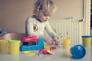 Cute girl playing with many colorful doughs.