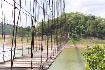 Obraz premium Suspension bridge on the river With mountains and sky in the background