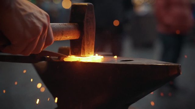 Slow motion close up of an hammer working on a hot horseshoe