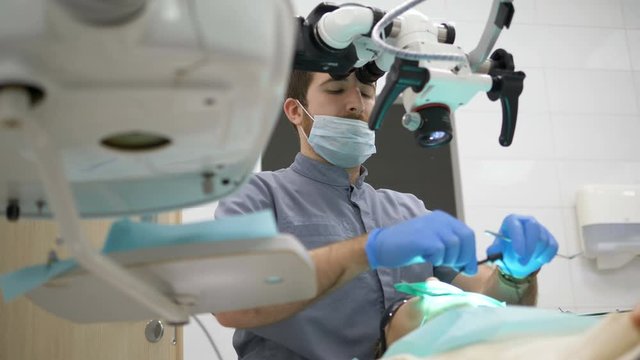 The dentist treats the patient's caries using a modern electronic microscope