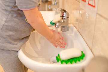a small child washes his hands under the tap in the bathroom, the topic of hygiene and health