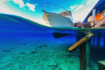 Over under view of seabed scuba diving boat and dock