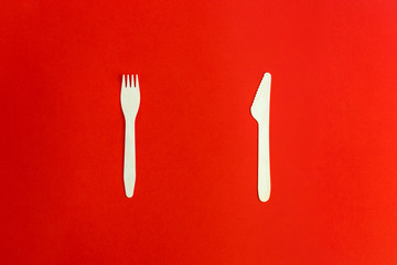 Wooden disposable fork and knife on red background, recycling and eco friendly concept. Zero waste,...
