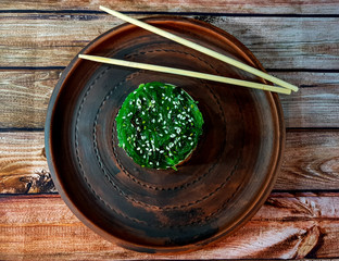 Healthy nutrition.Salmon, avocado and seaweed salad with sesame seeds on a dark wooden background.