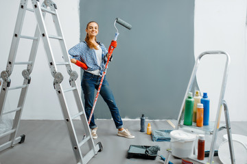 Cheerful female house painter paints walls indoor - obrazy, fototapety, plakaty