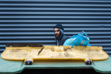 Bearded poor searching food in trashcan