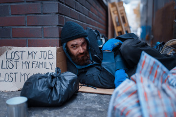 Bearded beggar sleeping on city street