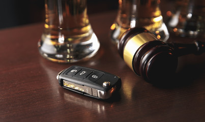 Drinking and driving concept. Car key on a wooden table, pub background