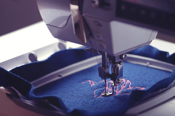 View on machine head and embroidery hoop of a modern sewing machine that stitches a magnolia with...