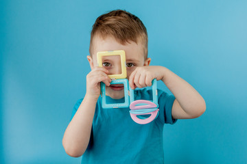 Boy looks through the shape in the color constructor with the connection of the magnets