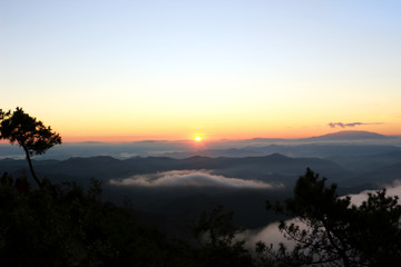 Beautiful scenery of mountain with mist sea, golden light shines on sky and sunrise up from the horizon at view point of Phu chi phoe in the early morning, Khun Yuam, Mae Hong Son, Thailand