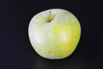 A large bright juicy green yellow apple, varieties Renet Simirenko is located on a black plastic background.