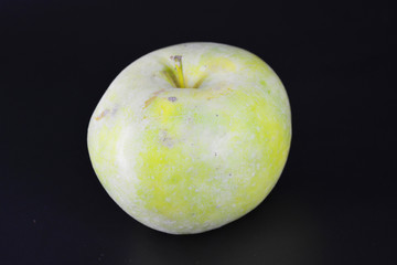 A large bright juicy green yellow apple, varieties Renet Simirenko is located on a black plastic background.