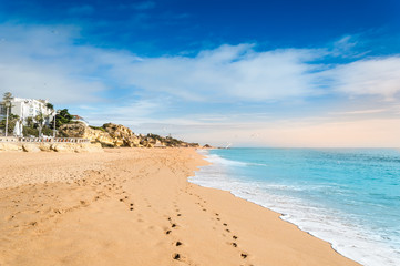 Sandy beach and hotels in Albufeira resort village in Algarve, Portugal at sunset.