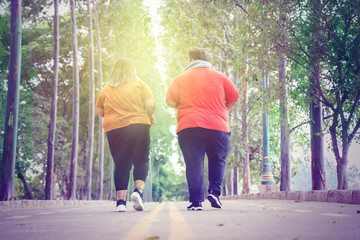 Unidentified fat couple jogging on the park road