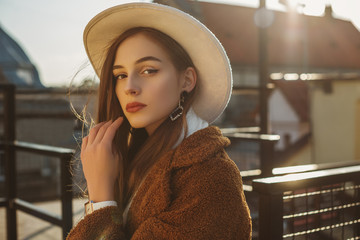 Young elegant fashionable brunette woman, model wearing stylish white hat, wrist watch, brown faux...