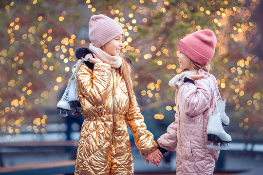 Adorable girls skating on ice rink outdoors in winter snow day - Powered by Adobe