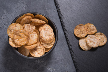 Top view pile of organic, crispy, baked, whole grain rice chips with spices. Gluten free healthy snack. Food background