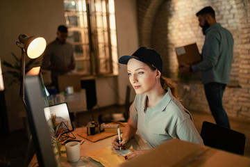 Obraz premium Female courier using computer while preparing package for a delivery.