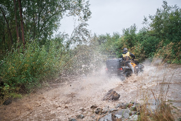 Quad rider jumping on a muddy forest trail.