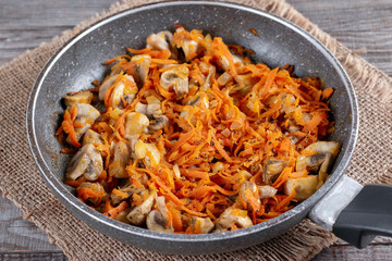 Fried onion and carrot with mushrooms on frying pan