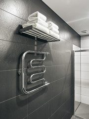 Bathroom toilet and towel warmer in hotel with grey walls and white towels
