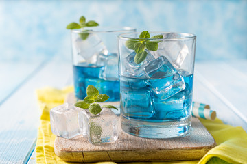 Blue lemonade in glasses on wood background, copy space