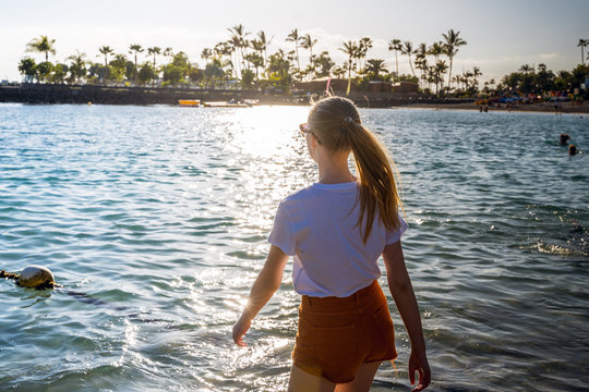 The girl  walking through ocean to palm trees in sunny day. Travel concept. 
