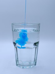 Glass of water with burst of blue color from water enhancer
