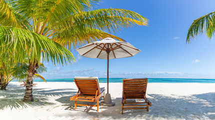 Beautiful tropical scenery, two sun beds, loungers, umbrella under palm tree. White sand, sea view with horizon, colorful twilight sky, calmness and relaxation. Inspirational beach resort hotel