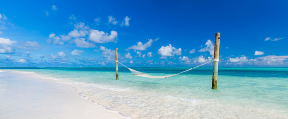 Romantic cozy hammock at tropical paradise ocean beach in bright sunny summer day. Summer beach vacation or holiday background