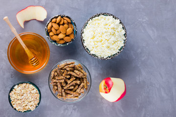Healthy diet breakfast. Ingredients for a healthy breakfast: oatmeal, granola, honey, almonds, apple, cottage cheese. Homemade granola on a gray background. Top view