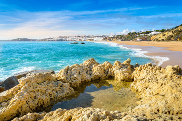 Fototapeta na wymiar Rock formations and sandy beach in Albufeira resort village in Algarve, Portugal.
