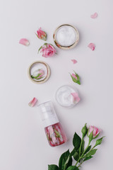 Homemade spa with rose cosmetic set, cream, rose water on white background. top view