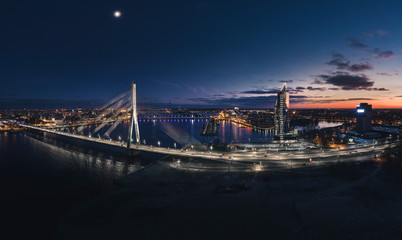 Aerial view over Riga city at night time. Urban landscape with skyscrapers and highway with city lights.